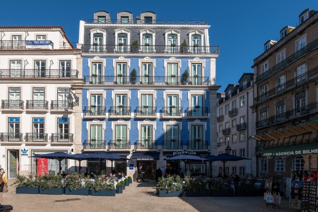 Charming blue facade of a Lisbon building with outdoor cafe seating under a clear sky.