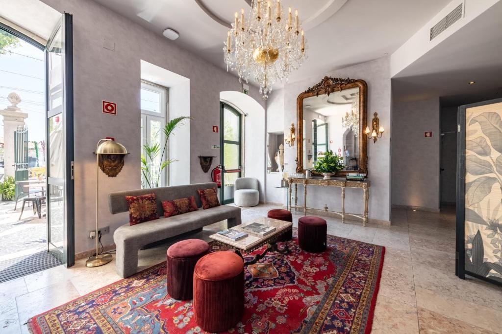 Luxurious hotel lobby with elegant chandelier, ornate mirror, plush seating, and vibrant red carpet.