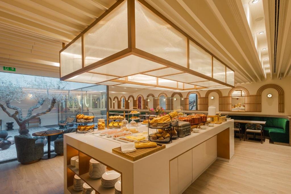 Luxurious hotel breakfast buffet with pastries and breads in elegant dining area with modern design and natural lighting.