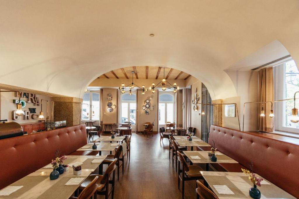 Stylish restaurant interior with elegant lighting, wooden tables, and red cushioned seating in a cozy ambiance.