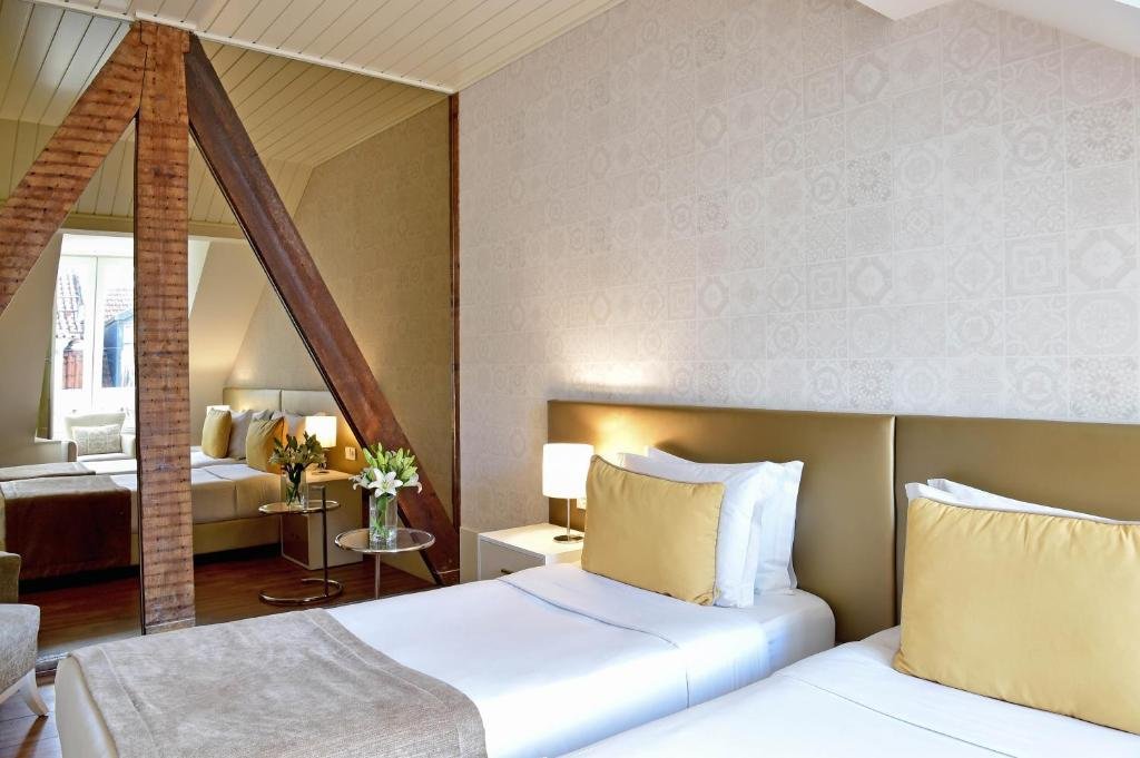 Cozy hotel room with twin beds, decorative pillows, and wooden beams, creating a warm and inviting atmosphere.
