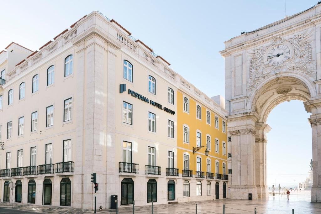 Historic Pestana Hotel near iconic Lisbon archway under a clear blue sky.