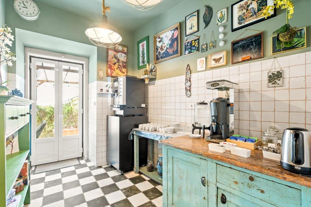 Vintage kitchen interior with retro decor, checkered floor, teal cabinets, and wall art, featuring a coffee station.