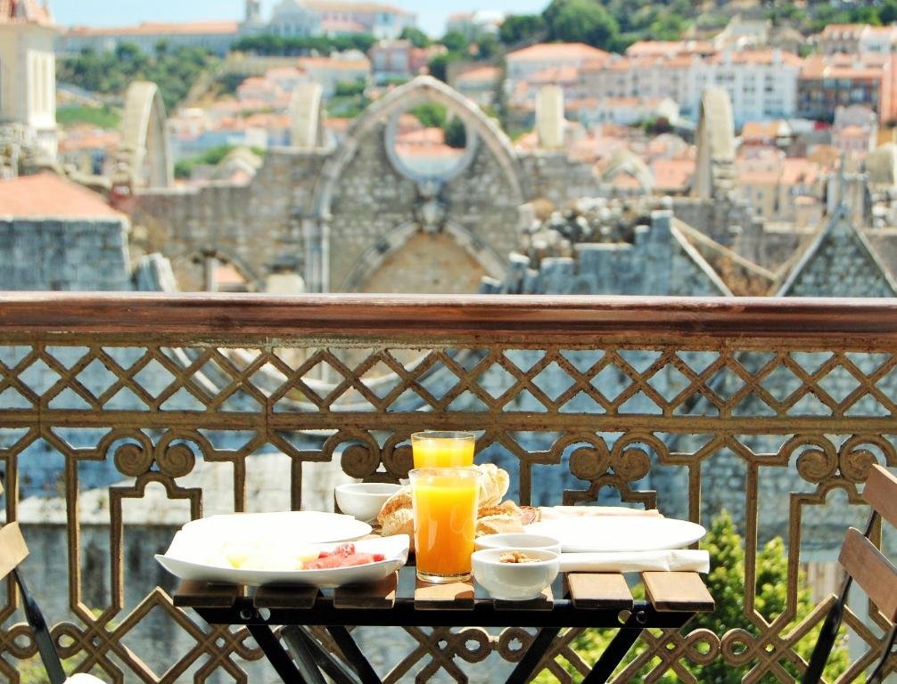 Breakfast with orange juice on a balcony overlooking a historic cityscape.