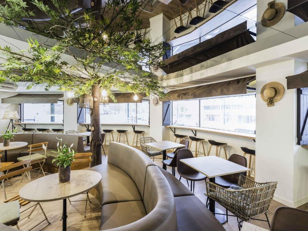 Modern cafe interior with tree centerpiece, cozy seating, and natural light. Stylish, inviting atmosphere.