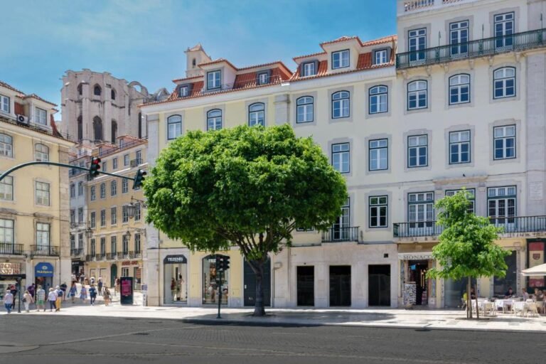 Historic Lisbon street scene with traditional architecture and lush trees under a clear blue sky.