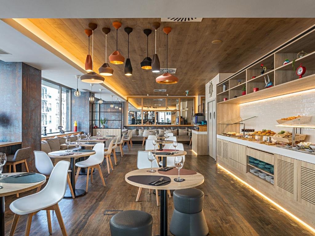 Modern restaurant interior with stylish lighting, wooden accents, and neatly set tables in a cozy, inviting atmosphere.