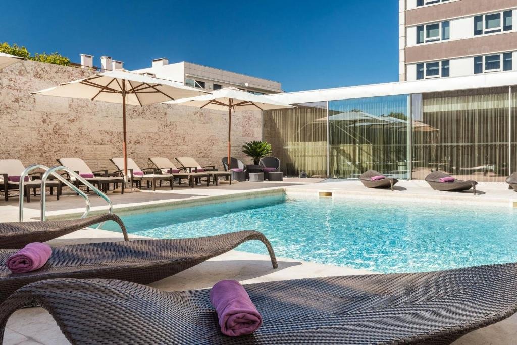Outdoor hotel pool with sun loungers, umbrellas, and towels, perfect for a relaxing summer day.