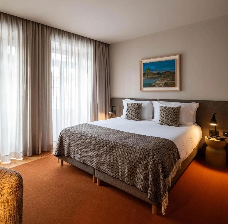 Cozy hotel room with a king-size bed, textured blanket, soft lighting, and modern decor.