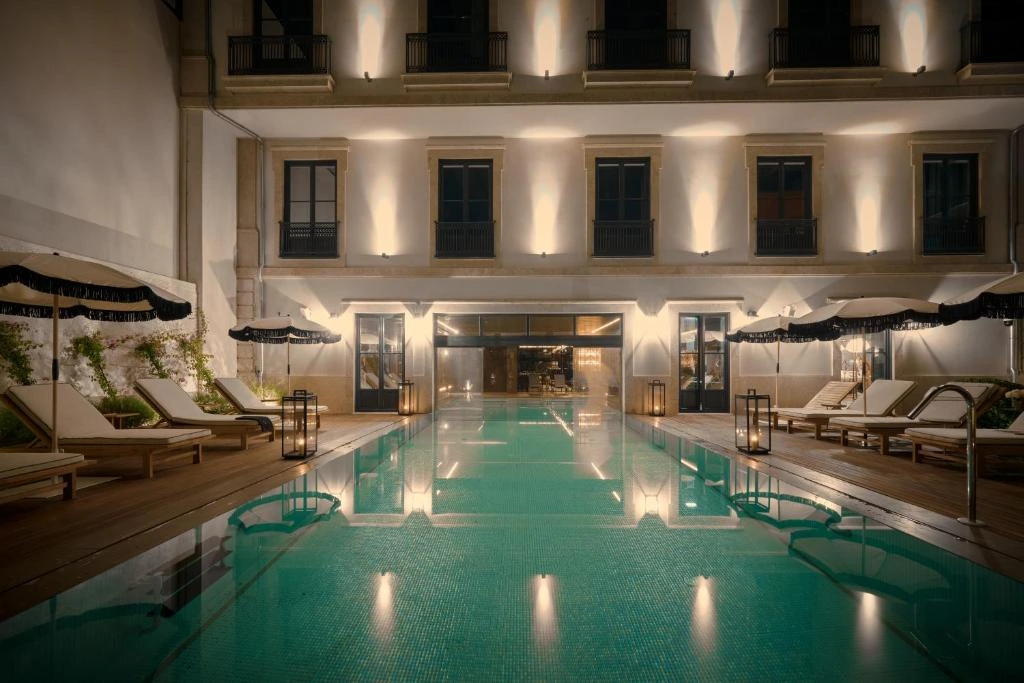 Luxurious outdoor hotel pool with sun loungers and ambient lighting, ideal for nighttime relaxation.