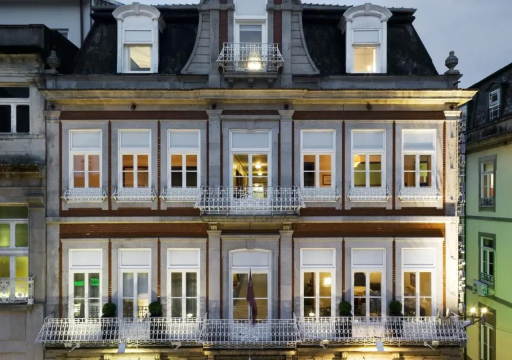 Elegant historic building facade with illuminated windows and intricate balconies at dusk.