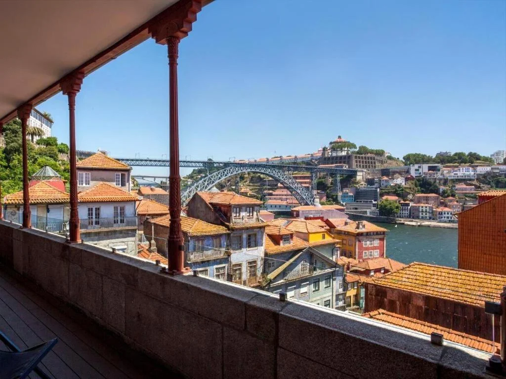 View of Porto's rooftops and Dom Luís I Bridge over the Douro River on a sunny day.