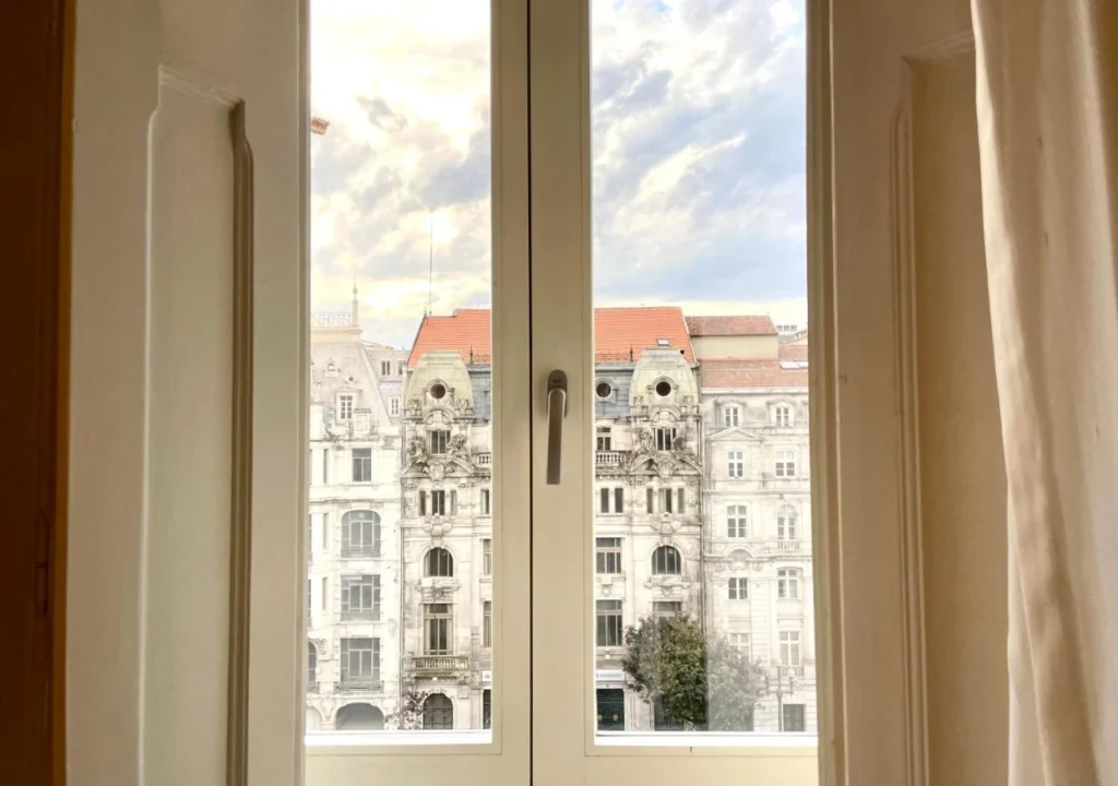View through a window of historic European architecture under a partly cloudy sky.