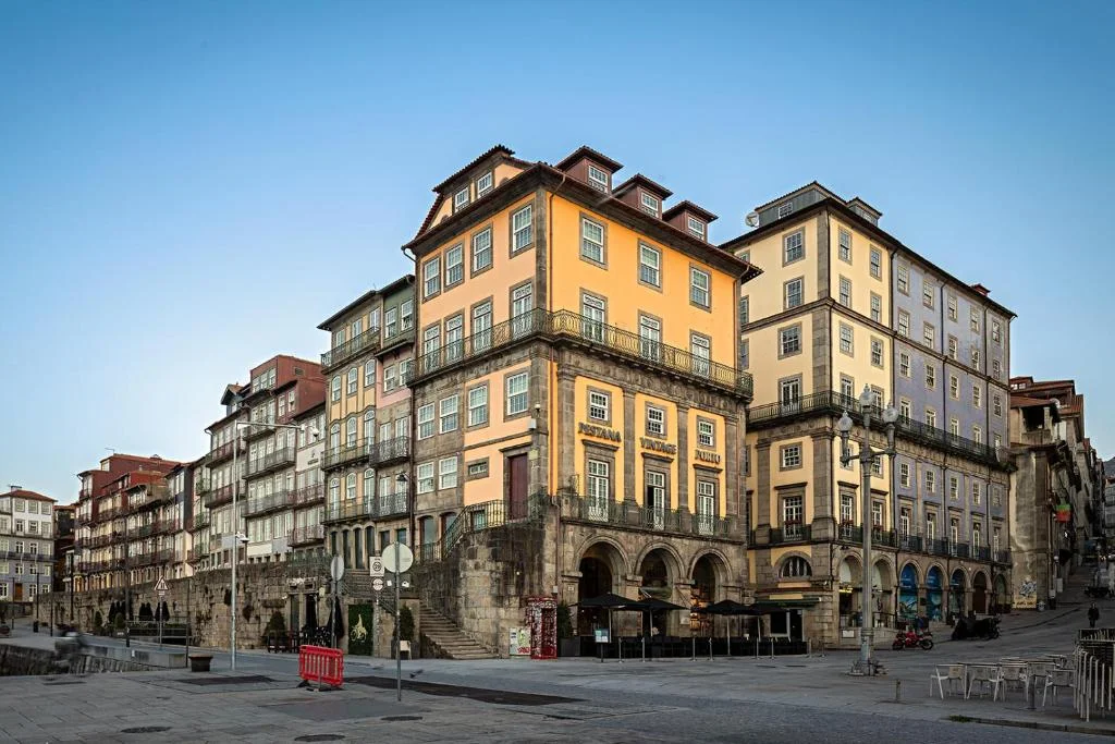 Colorful Ribeira Square buildings with archways in Porto, Portugal, during a clear day.