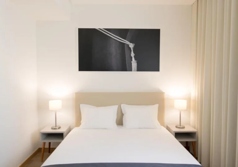 Minimalist hotel room with a cozy bed, soft lighting, and modern decor for a relaxing stay.