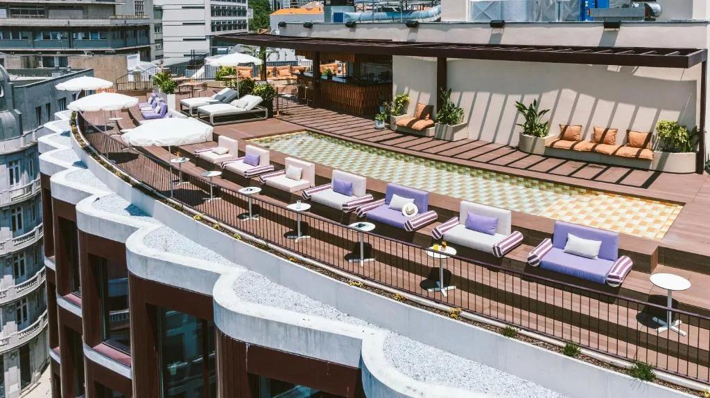 Rooftop pool with loungers and umbrellas, offering a relaxing urban oasis with cityscape views.