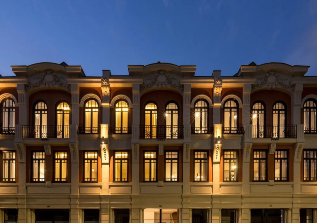Elegant historic building facade lit up at night, showcasing arched windows and intricate architectural details.