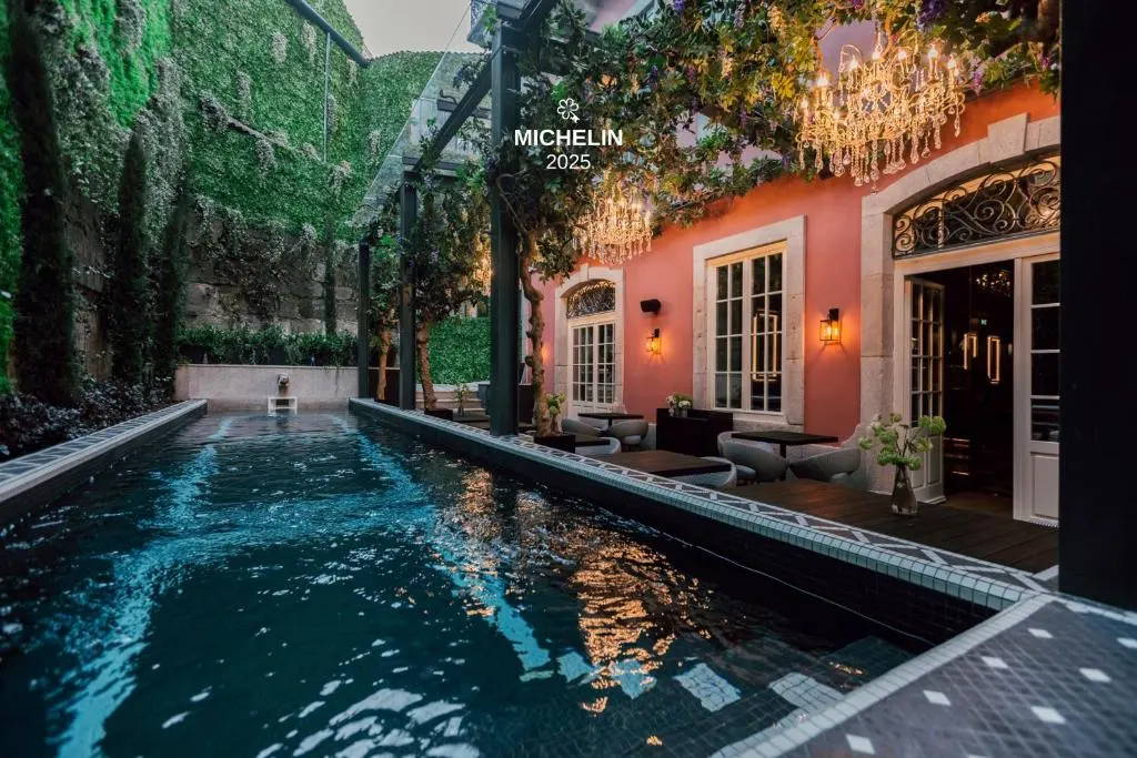 Luxurious courtyard with a pool, elegant chandeliers, and ivy-covered walls at a Michelin-starred restaurant.