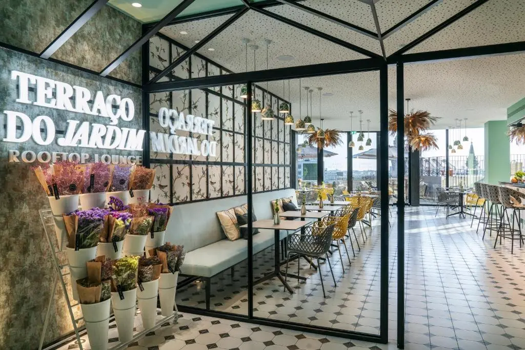 Chic rooftop lounge with floral decor, pastel seating, and city views, offering a stylish and relaxing ambiance.